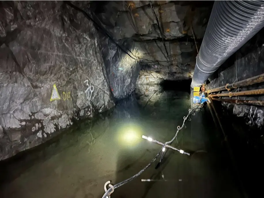 Figure 1: Dewatering continues, with XC4 in background, as denoted by cut out on the left, and the yellow signage to the Mine Refuge chamber next to services on the right. Photo taken 27th November 2025